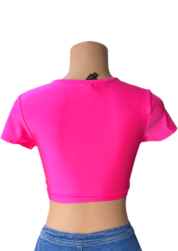 Vista de espalda. Blusa corta de color rosado, con un diseño cruzado en la parte frontal que resalta el escote en V profundo.