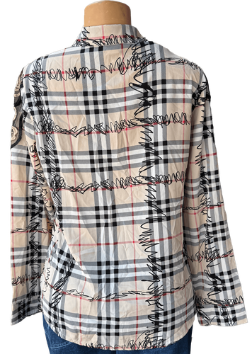 Vista de espalda (dos de tres). Una blusa de manga larga con un estampado de cuadros en tonos crema y detalles bordados en negro.