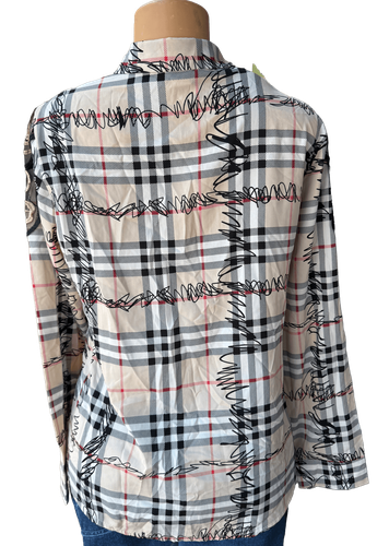 Vista de espalda (tres de tres). Una blusa de manga larga con un estampado de cuadros en tonos crema y detalles bordados en negro.