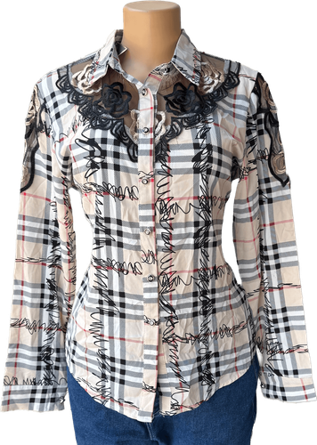 Vista de frente (dos de dos). Una blusa de manga larga con un estampado de cuadros en tonos crema y detalles bordados en negro.