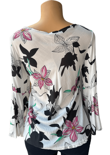 Vista de espalda (una de dos). Una blusa blanca de manga larga con un estampado de flores en tonos negros, rosas y verdes.