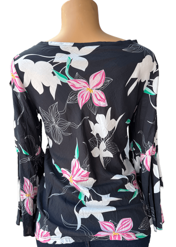 Vista de espalda (una de dos). Una blusa negra de manga larga con un estampado de flores en tonos blancos, rosas y verdes.