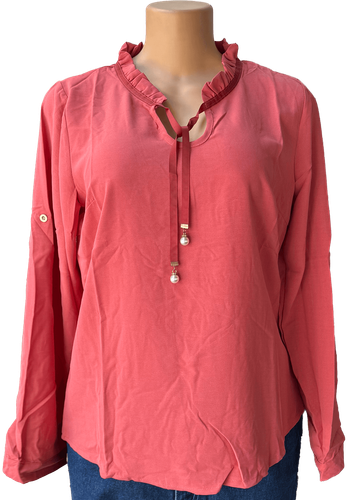 Vista de frente (dos de dos). Una blusa roja de manga larga con cuello fruncido y detalle de lazo con perlas.