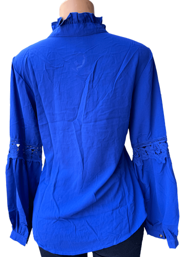 Vista de espalda (dos de dos). Una blusa de manga larga azul con detalles de encaje en las mangas y cuello alto.