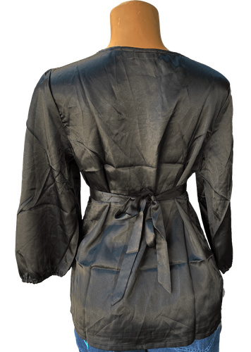 Vista de espalda (una de dos). Una blusa negra simple con mangas largas y un cinturón ajustable en la cintura.