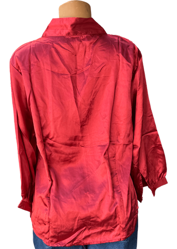 Vista de espalda (una de dos). Blusa de satén con mangas largas y un diseño clásico de botones en la parte frontal.