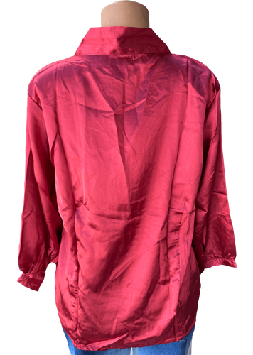 Vista de espalda (dos de dos). Blusa de satén con mangas largas y un diseño clásico de botones en la parte frontal.