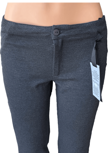 Vista de frente (dos de dos). Pantalón estirado de color gris con cierre frontal y bolsillos laterales.